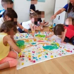 Profesora y niños del centro infantil Goofy pintando un mural